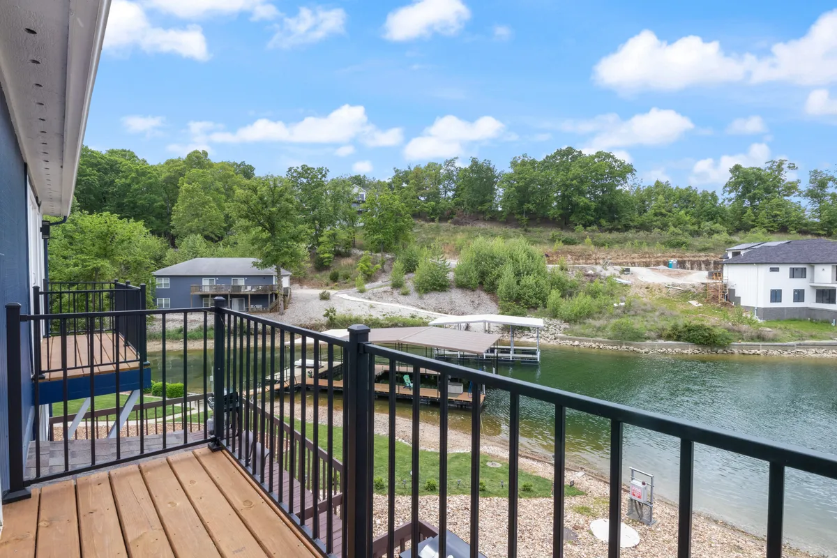 A tranquil lakeside scene featuring a spacious dock surrounded by lush greenery. The dock extends over the calm waters of the cove and offers space for lounging, with visible areas to gather and relax. The background showcases the serene lake, ideal for boating and swimming, while the dock easily accommodates activities like sunbathing and socializing.