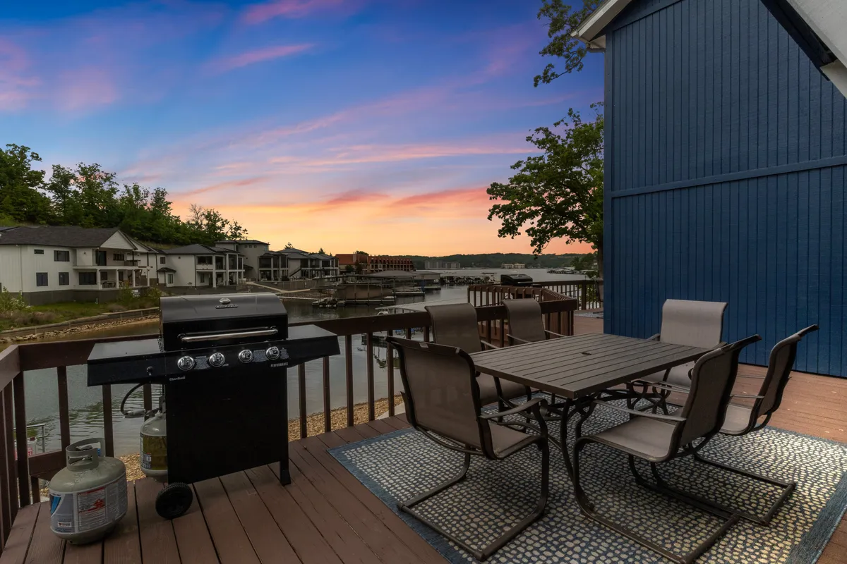 The hero image showcases an inviting outdoor space featuring a grill and dining table set up on a patio, overlooking serene lake waters. The view is enhanced by a vibrant sunset sky, casting a warm glow on the scene, and suggesting an ideal spot for outdoor dining, relaxation, and social gatherings right by the lake.