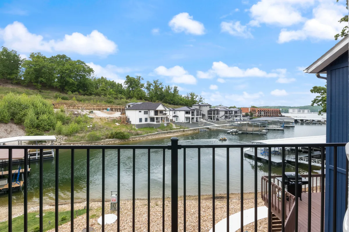 A scenic waterfront view with calm waters, boats, modern homes, and lush green hills in the background. The setting evokes peaceful outdoor leisure and socializing by the water—perfect for family-oriented water play and relaxation.