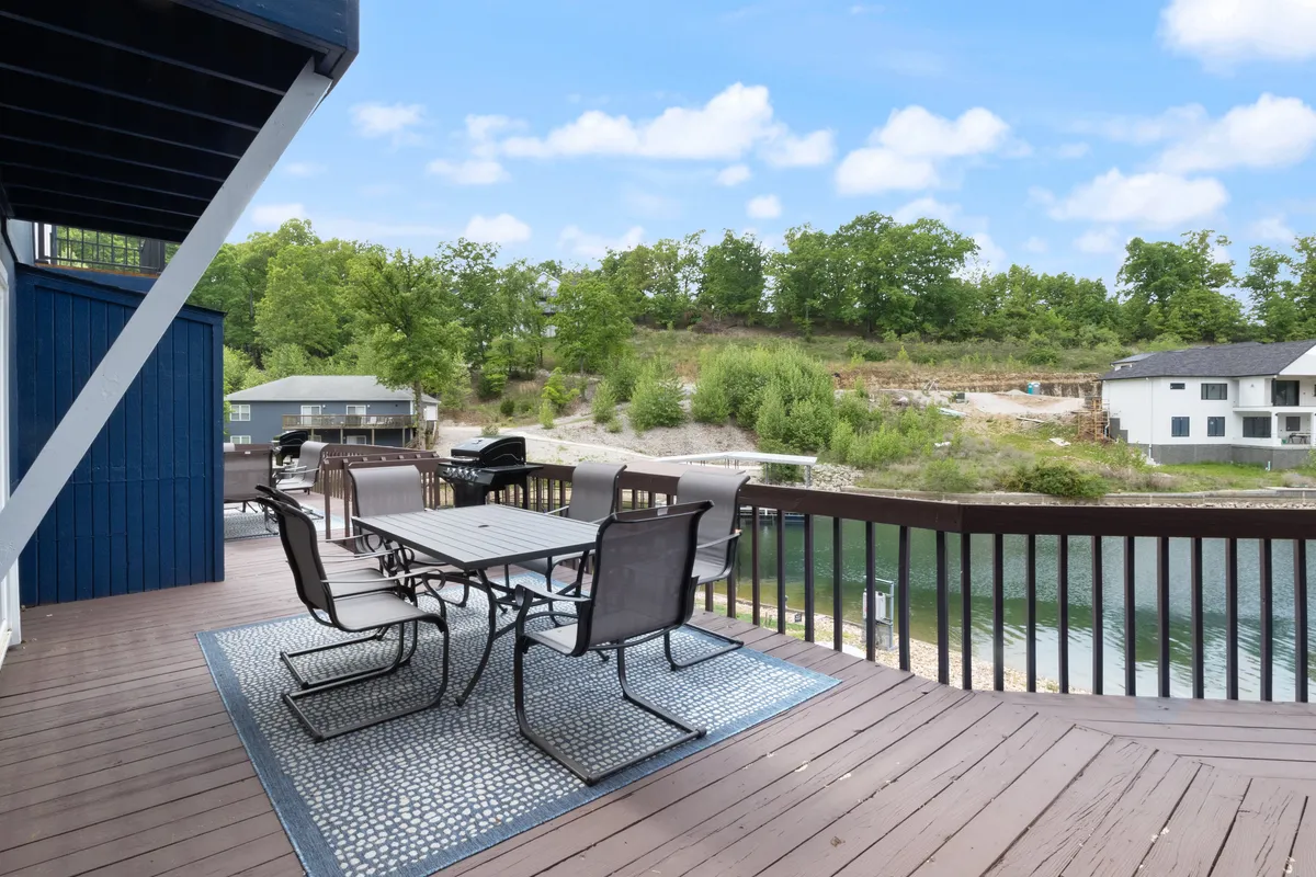 A well-appointed dockside patio scene with an outdoor dining table, chairs, and a grill, all positioned to maximize the lake view. The space is designed for both relaxing and entertaining, inviting guests to enjoy barbecues, sunset dinners, or quiet mornings by the water.