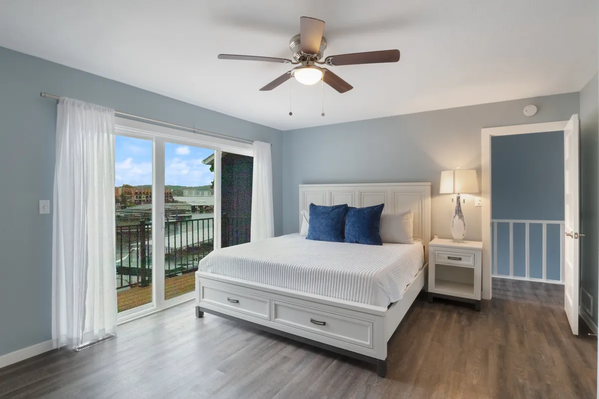 A serene bedroom with a plush bed and a sizable window that frames peaceful views of the outdoors. Soft, natural light pours in, inviting guests to relax, read, or simply take in the tranquil lakeside surroundings.